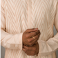 Close-up of a person wearing a pink patterned kurta with hands clasped together.